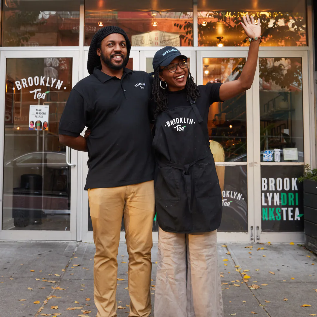 2 Brooklyn Tea workers posing in uniform and smiling