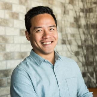 Marko Sotto, owner at Barzotto, smiling in front of a brick wall.