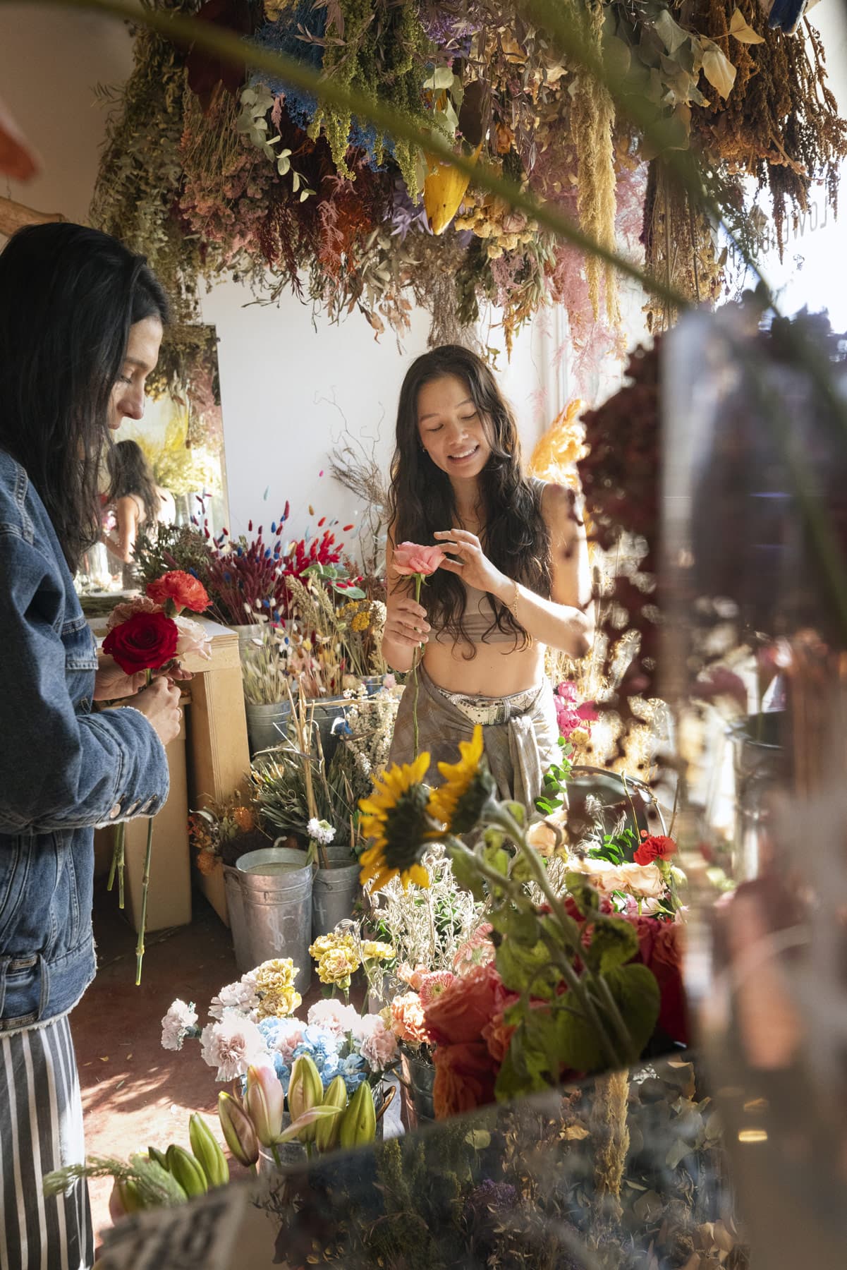 Two florists arranging bouquets behind the counter of a flower shop.