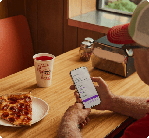 A restaurant worker checking his pay details on his phone during a break.