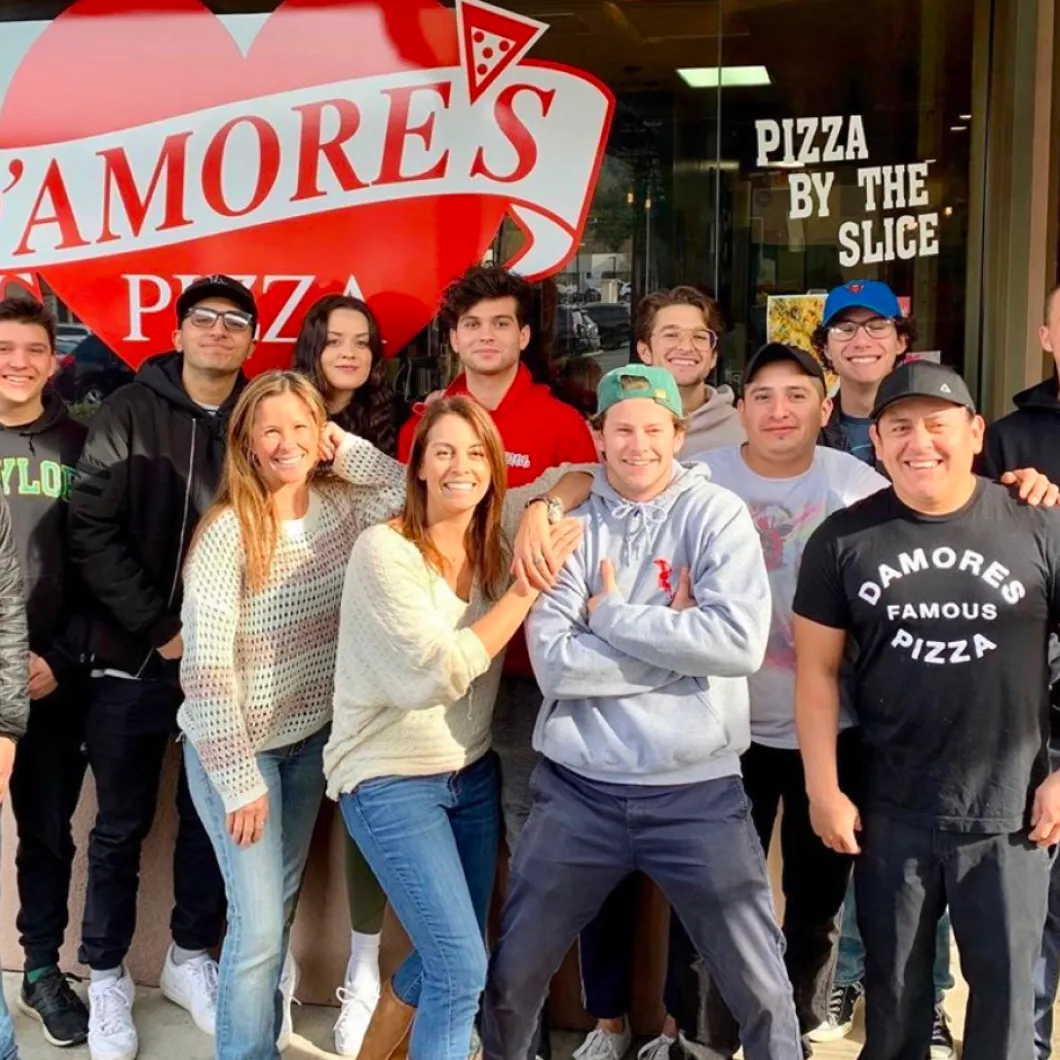 A group posing in front of Amore's Pizza