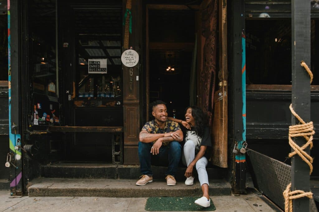 A Black couple sitting outside their new business.