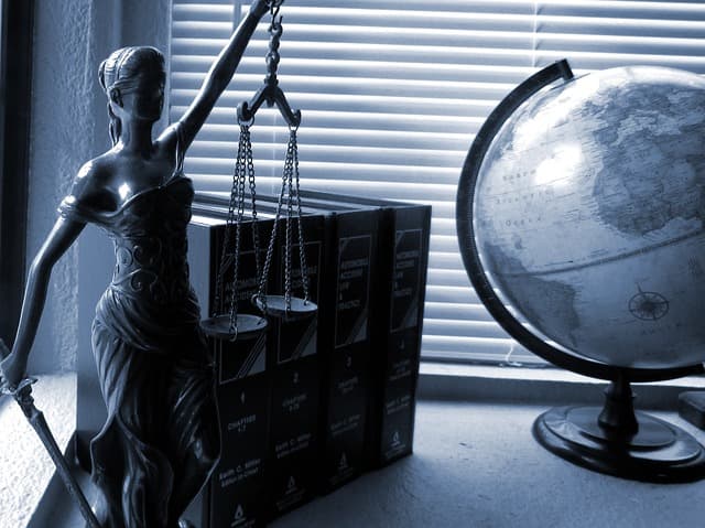 Globe next to books and woman holding balance scale background image