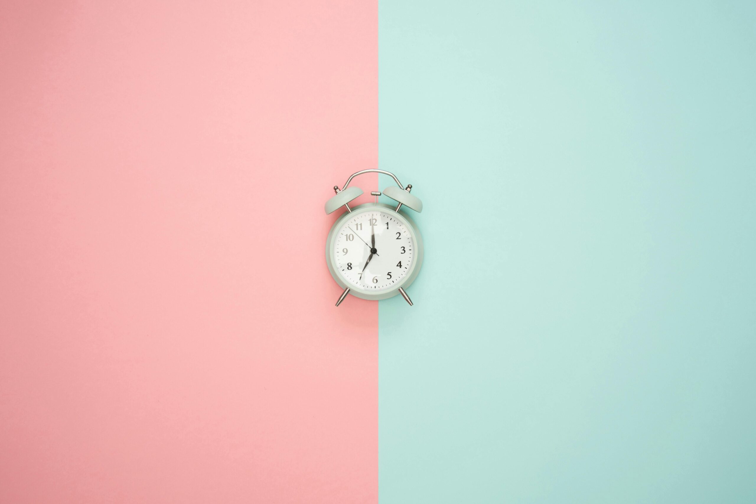 Alarm clock on blue and pink background
