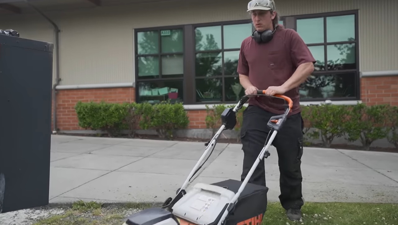 A screenshot of the Trevor Kokenge interview on the UpFlip YouTube channel, showing the business owner using a lawn mower.