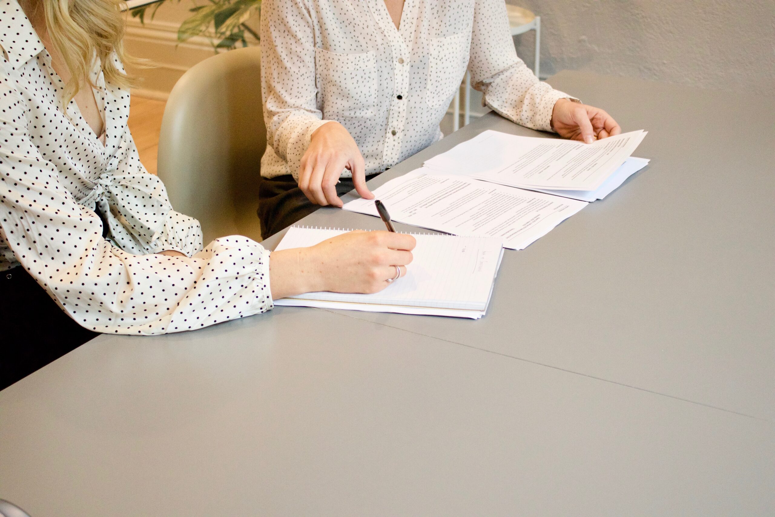 Woman signing documents in front of another woman